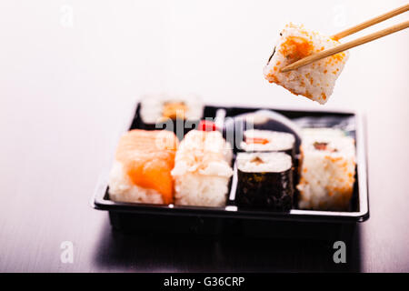 ein Sushi oder Bento Box mit verschiedene Sushi-Stücke über eine dunkle Holzoberfläche Stockfoto