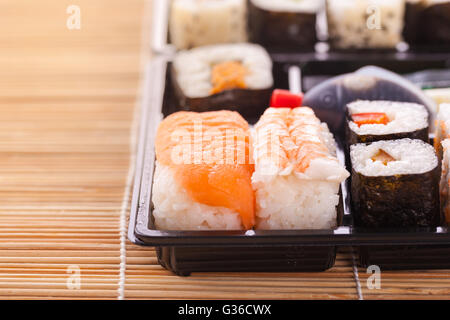 Sushi zum Mitnehmen Plastikschale Box auf einer hölzernen Sushi Bambusmatte Stockfoto