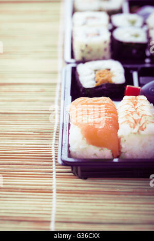 Sushi zum Mitnehmen Plastikschale Box auf einer hölzernen Sushi Bambusmatte Stockfoto