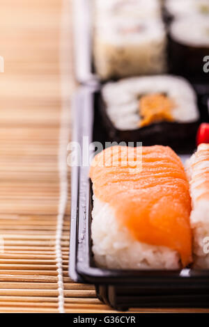 Sushi zum Mitnehmen Plastikschale Box auf einer hölzernen Sushi Bambusmatte Stockfoto