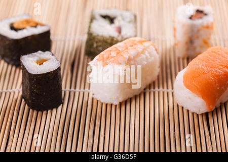 eine Auswahl an verschiedenen Sushi-Stücke auf einer hölzernen Sushi Bambusmatte in einem japanischen restaurant Stockfoto