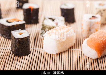 eine Auswahl an verschiedenen Sushi-Stücke auf einer hölzernen Sushi Bambusmatte in einem japanischen restaurant Stockfoto