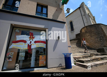 Eine Frau steigt die Stufen der St.-Georgs Kirche angrenzend an einem Schaufenster anzeigen willkommen Banner die Nationalmannschaft von Nordirland in der Nähe von Teamtraining im St. Georges de Reneins, Frankreich. Stockfoto