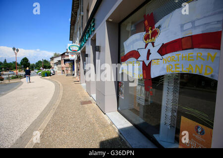 Eine Frau geht weg von einem Schaufenster anzeigen willkommen Banner die Nationalmannschaft von Nordirland in der Nähe der Team-Trainingslager in St. Georges de Reneins, Frankreich. Stockfoto