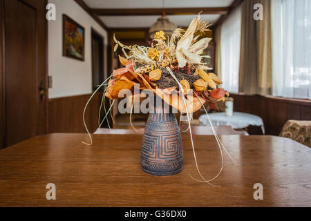 eine Vase mit einigen dekorativen getrockneten Blüten auf einem Couchtisch Stockfoto