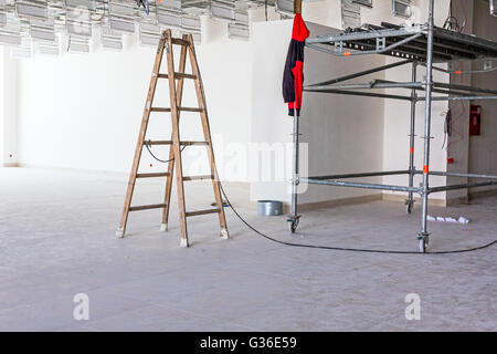 Arbeiter dienen Holzleiter abgehängte Büro Decke auf der Baustelle abgeschlossen. Stockfoto