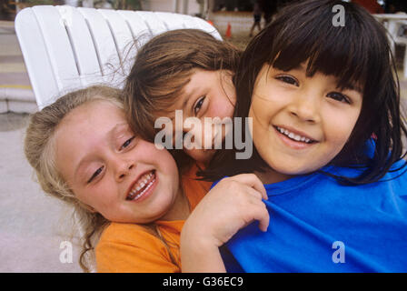 3 Kinder umarmen multi-ethnischen Gruppe Stockfoto