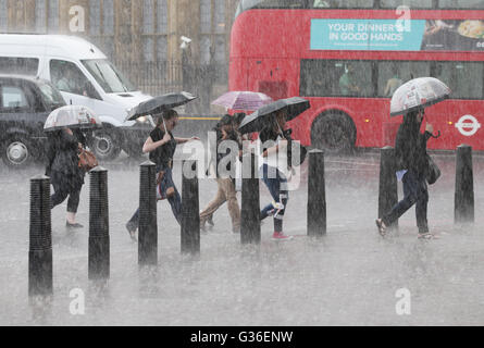 Menschen sind gefangen in einem schweren Regenschauer in Westminster, London. Stockfoto