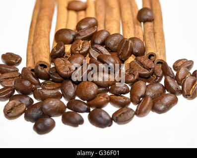 Kaffeebohnen-Heap vor paar Zimt sticks vor weißem Hintergrund Stockfoto