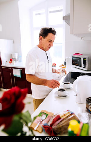 Senior woman Zubereitung von Kaffee. Setzen Zucker in Tassen. Stockfoto