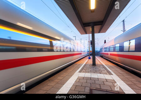 High-Speed Personenzüge auf Eisenbahn-Plattform in Bewegung in der Abenddämmerung. Verschwommen, s-Bahn. Bahnhof in Nürnberg, Deutschland Stockfoto