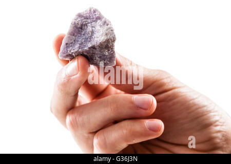 eine männliche Hand, die ein Fragment der Lepidolith Mineral isoliert auf weißem Hintergrund Stockfoto