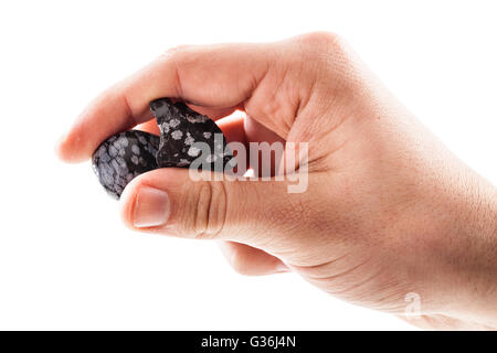 eine männliche Hand, die ein Fragment der Obsidian Mineral isoliert auf weißem Hintergrund Stockfoto