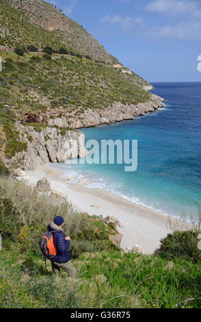 Wanderer auf einem Pfad entlang Meer und Cala Tonnarella dell'Uzzo im Zingaro natural reserve, Sizilien Stockfoto