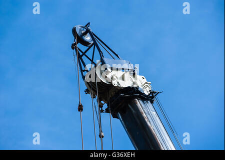 Große schwere industrielle Riemenscheiben und Kabel auf blauen und weißen Kran auf wolkenlos blauen Himmel, Horizontal gedreht. Stockfoto