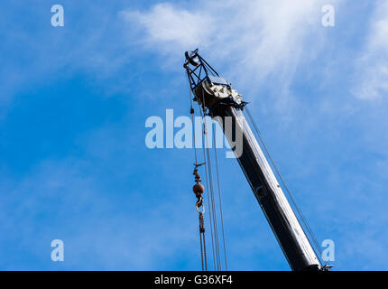 Spitze der großen schweren Industriekran in Himmel, Riemenscheiben und Kabel von oben mit Gewicht und Ketten hängend erweitert. Stockfoto