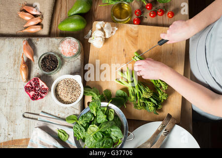 Aufwand für Kochen Brokkoli auf Holzbrett mit Spinat, Cherry-Tomaten, Avocados und andere Gewürze neben hacken Stockfoto