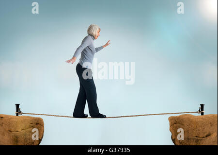 ältere Frau zu Fuß auf einem Drahtseil Stockfoto