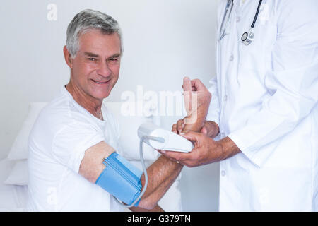 Arzt überprüft Senior mans Blutdruck Stockfoto