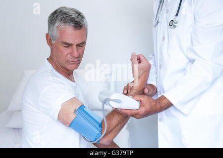 Arzt überprüft Senior mans Blutdruck Stockfoto