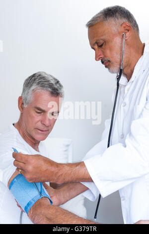 Arzt überprüft Senior mans Blutdruck Stockfoto