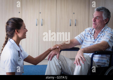 Ärztin, tröstende senior Mann im Wohnzimmer Stockfoto