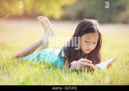 Junges Mädchen auf dem Rasen liegen und Buch im park Stockfoto