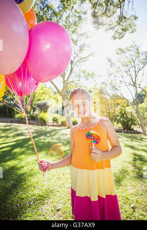 Porträt von lächelndes Mädchen mit Luftballons und Lutscher im park Stockfoto