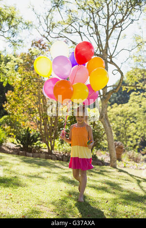 Mädchen zu Fuß mit Lutscher und Luftballons im park Stockfoto