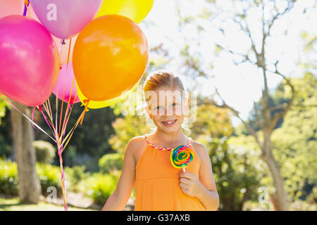 Porträt von lächelndes Mädchen mit Luftballons und Lutscher im park Stockfoto