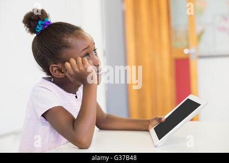 Nachdenklich Schulmädchen mit digital-Tablette im Klassenzimmer Stockfoto