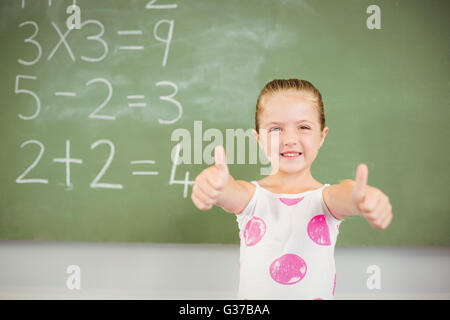 Porträt des Lächelns Schulmädchen zeigt Daumen oben im Klassenzimmer Stockfoto