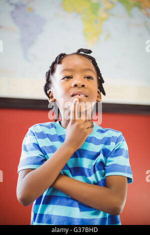 Nachdenklich Schuljunge stehend mit Hand am Kinn im Klassenzimmer Stockfoto