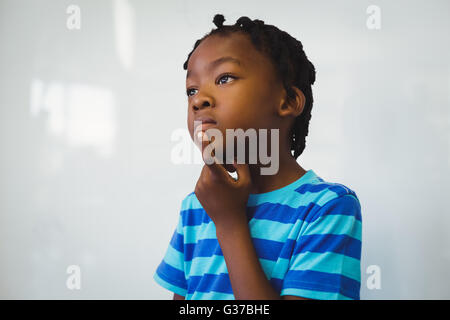 Nachdenklich Schuljunge stehend mit Hand am Kinn im Klassenzimmer Stockfoto