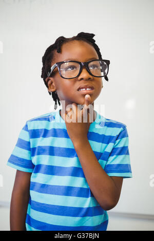 Nachdenklich Schuljunge stehend mit Hand am Kinn im Klassenzimmer Stockfoto