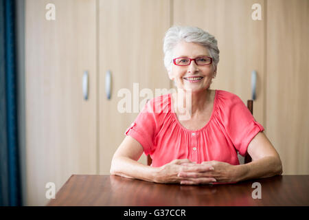 Ältere Frau sitzt an einem Tisch Stockfoto