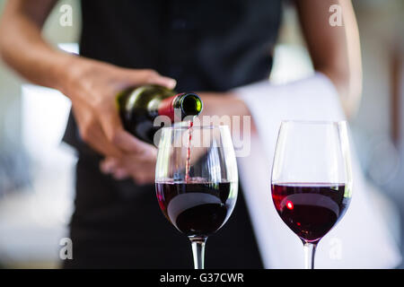 Mittleren Bereich der Kellnerin Rotwein in ein Glas gießen Stockfoto