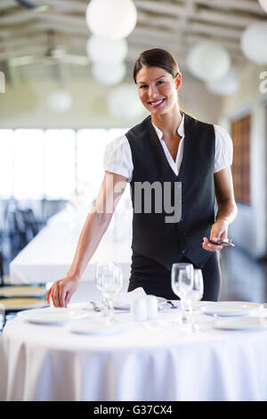 Porträt von lächelnden Kellnerin Tischdecken Stockfoto