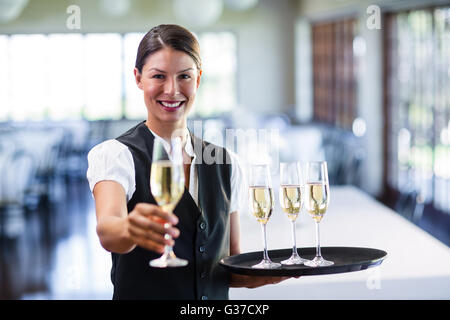 Porträt von lächelnden Kellnerin mit einem Glas Champagner Stockfoto