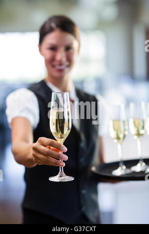 Porträt von lächelnden Kellnerin mit einem Glas Champagner Stockfoto