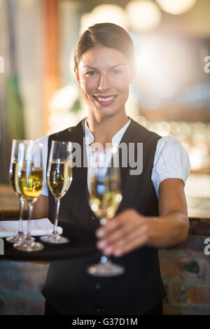 Porträt von lächelnden Kellnerin mit einem Glas Champagner Stockfoto