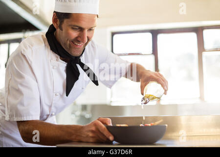 Koch gießen Öl auf Essen Stockfoto