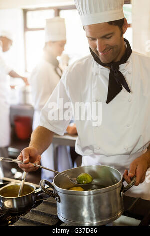 Lächelnde Küchenchef rühren im Topf Stockfoto