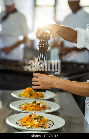 Koch, Prise Pfeffer auf eine Mahlzeit Stockfoto