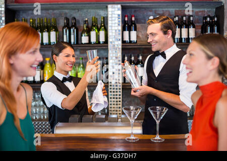 Freunde stehen am Schalter während der Barkeeper einen Drink vorbereiten Stockfoto