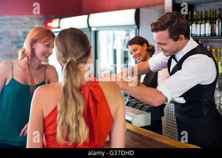 Freunde stehen am Schalter während der Barkeeper einen Drink vorbereiten Stockfoto