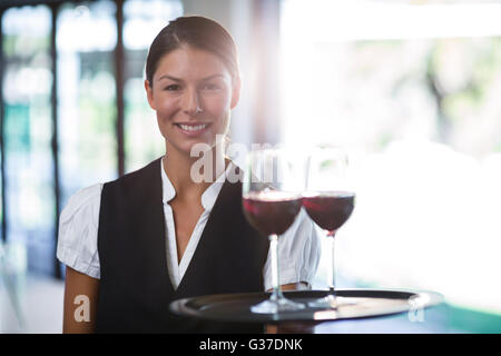 Lächelnd hält ein Tablett mit Gläsern Rotwein Kellnerin Stockfoto