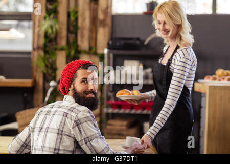 Kellnerin mit einem Kaffee an einem Kunden Stockfoto