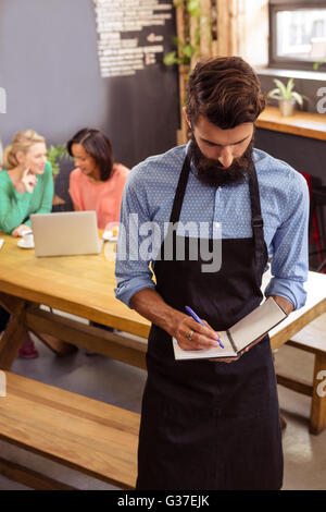 Kellner die Bestellung in seinem Buch Stockfoto