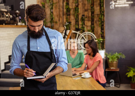 Kellner die Bestellung in seinem Buch Stockfoto